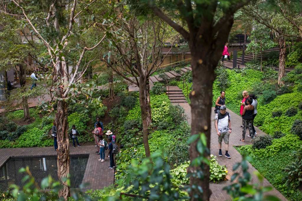 A group of people strolling through green gardens at the Ford Foundation Center for Social Justice.